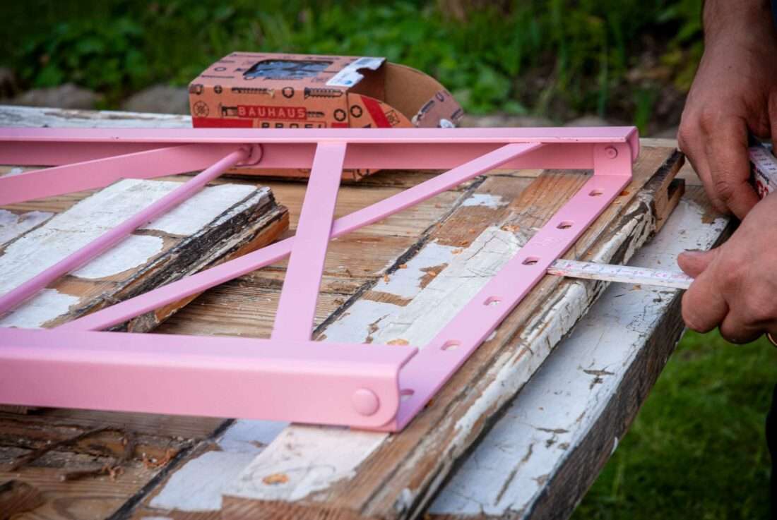 Klapptisch selber bauen: Ein Mann misst den Platz für das erste Tischbein aus.