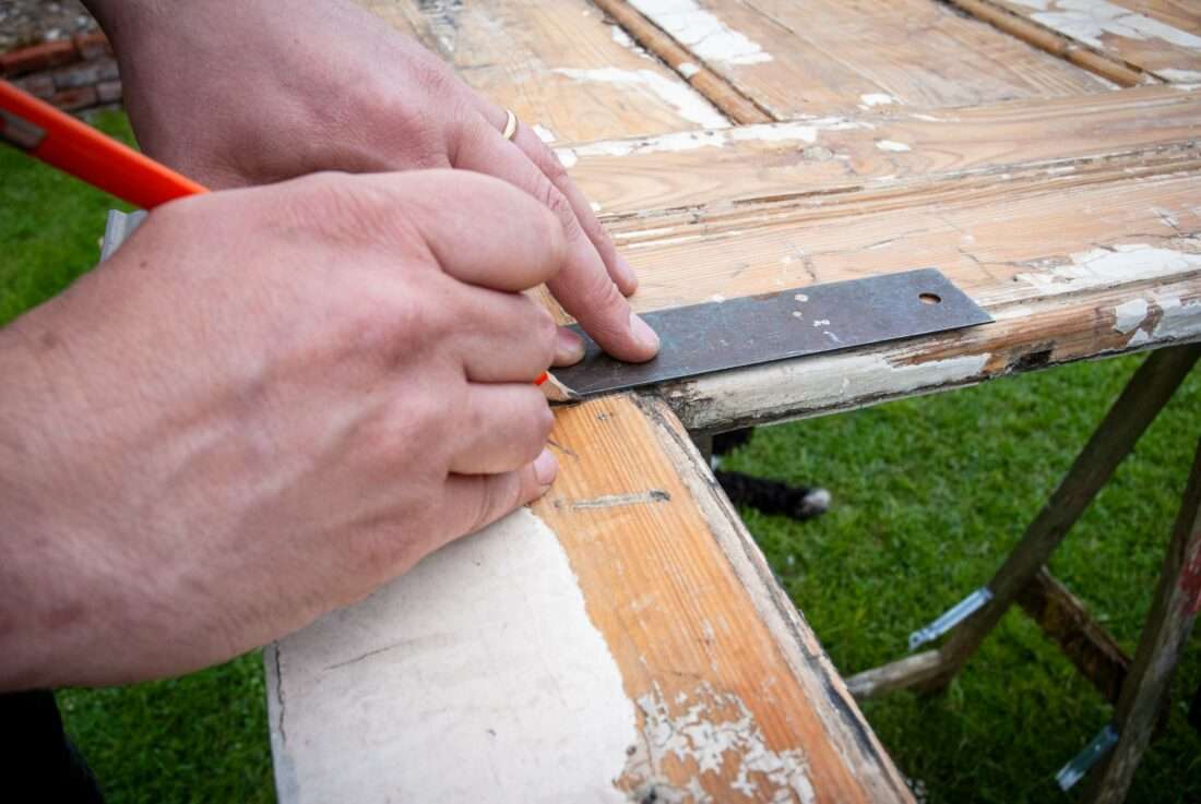 Ein Mann zeichnet eine Linie auf eine Tür, aus dem ein Klapptisch gebaut wird.