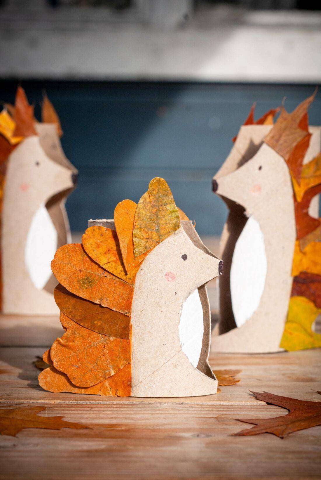 Eine Familie aus LAub gebastelter Igel steht auf einem Tisch. 