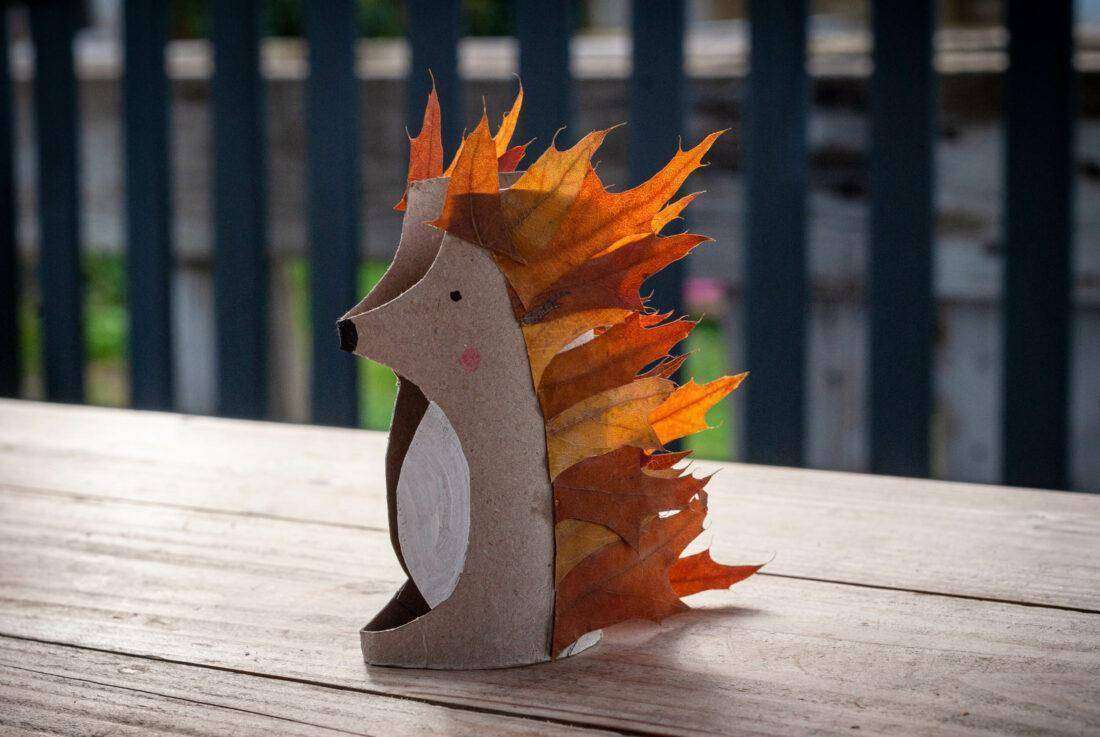 Ein aus Laub gebastelter Igel steht auf einem Gartentisch. 